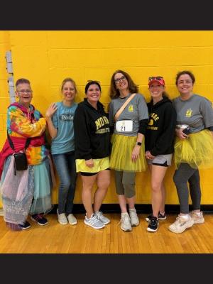 Six people after the 2024 MCC Run/Walk, some wearing tutus, all wearing smiles.